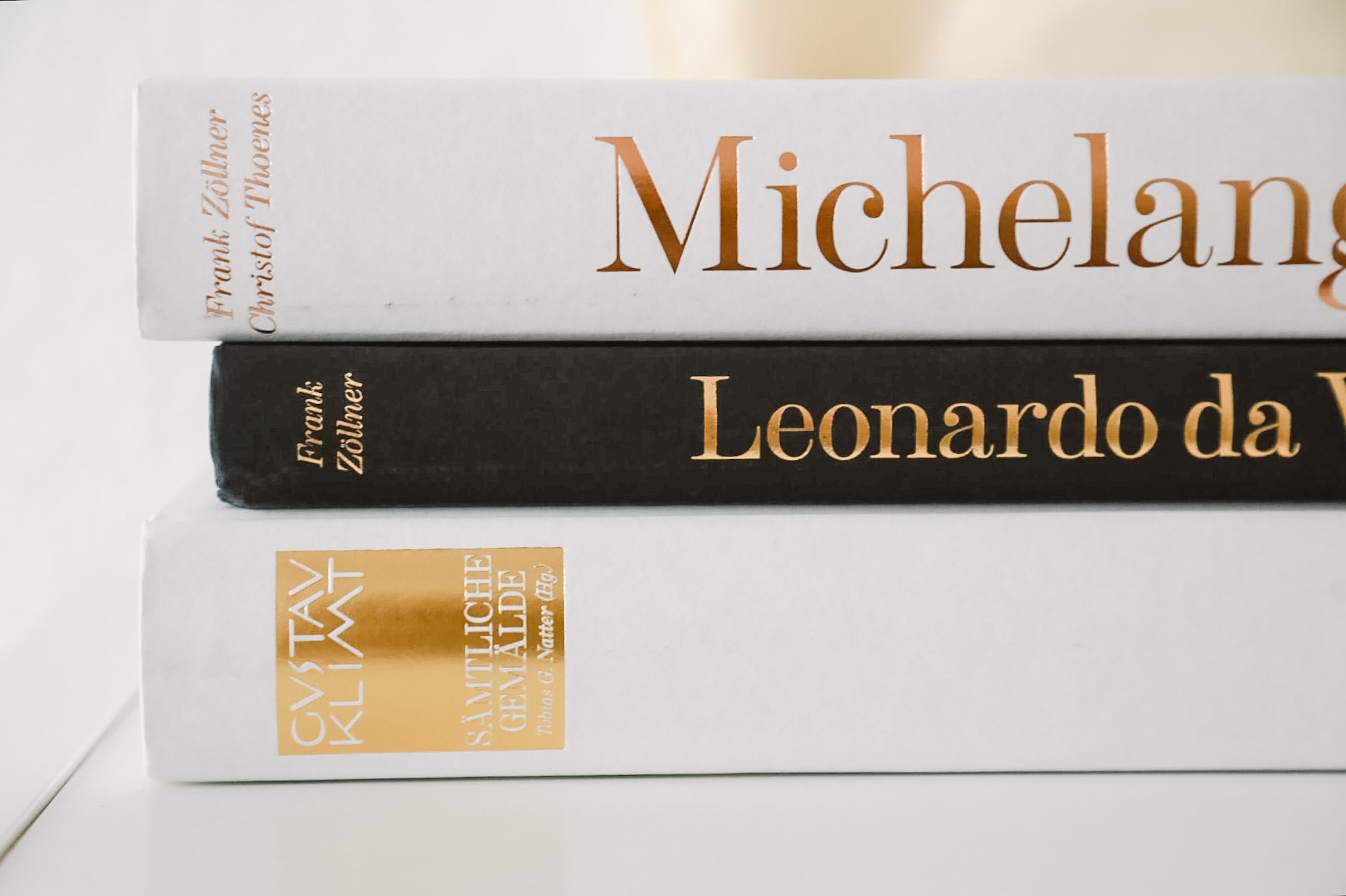 Stacked art books with the artist names Michelangelo and Leonardo da Vinci printed on their spines.